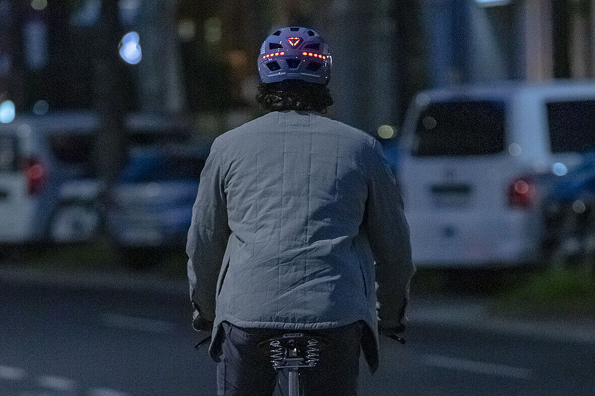 Mann auf Fahrrad mit Helm, der hinten rot leuchtet